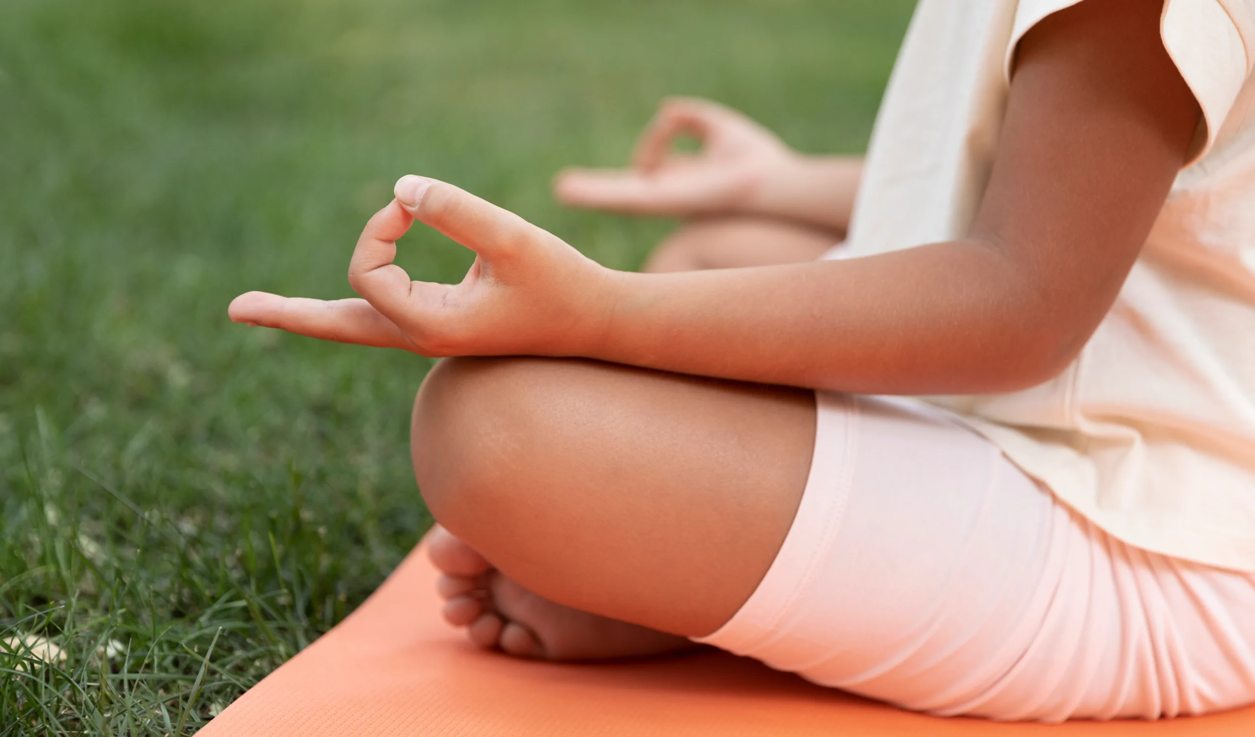 Blog yoga bien-être : Personne assise en tailleur sur un tapis de yoga, les mains posées sur les genoux en posture de méditation