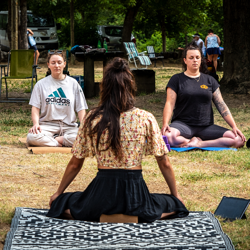 Marylou Forges, fondatrice de Yoga Le Refuge à Saint-Rome-de-Tarn, guidant une séance de yoga en bord de rivière avec des participantes assises en méditation