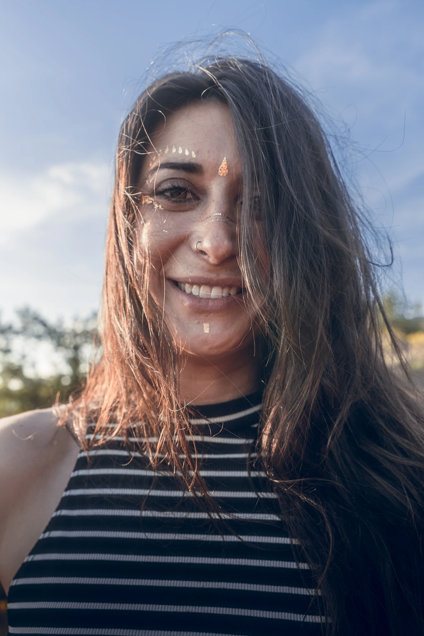 Portrait de Marylou Forges, professeure de yoga et fondatrice de Yoga Le Refuge à Saint-Rome-de-Tarn, souriante en extérieur sous le soleil