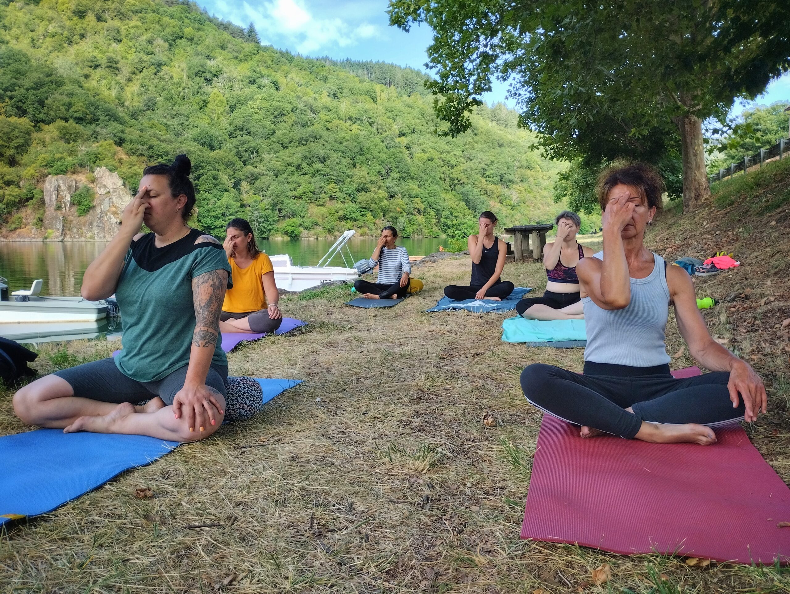 Groupe d'élèves de yoga réalisant la respiration alternée en plein air au bord du Tarn pendant une séance estivale
