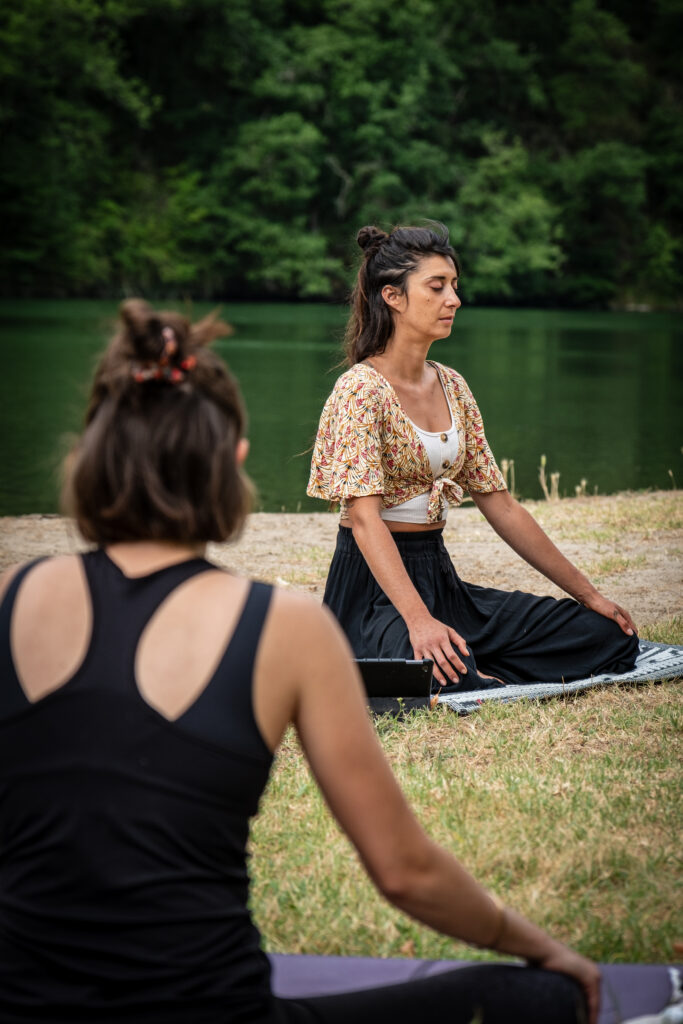 Femmes assises en Sukhasana, posture de méditation en tailleur, pratiquant le yoga et la pleine conscience en pleine nature.