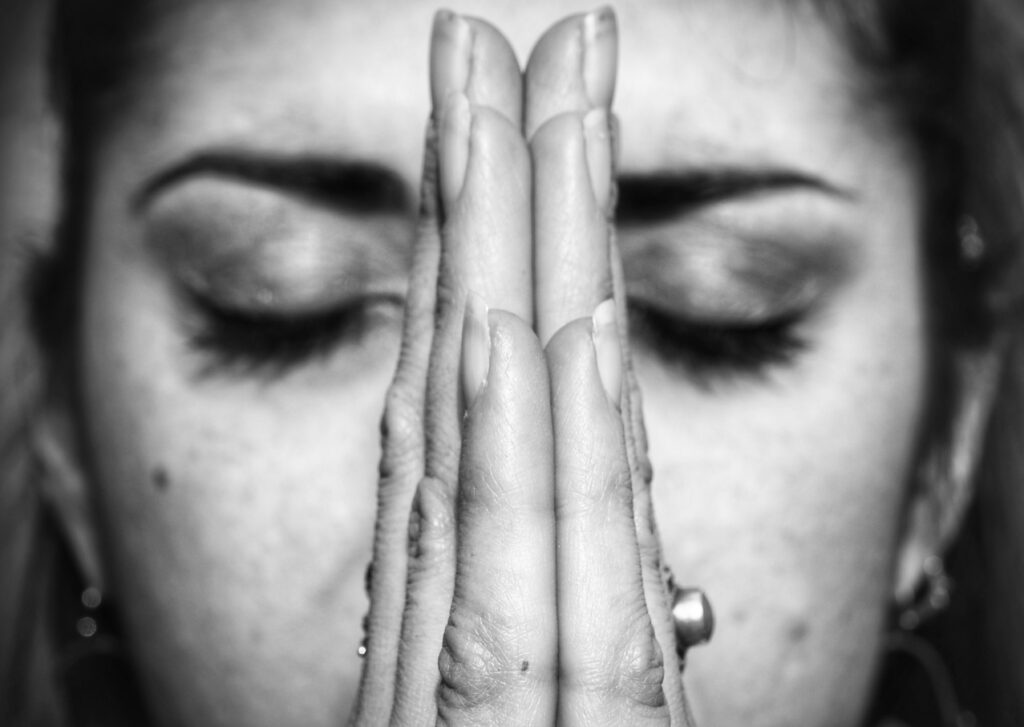 Posture de prière (Anjali Mudra, Namaste) les yeux fermés, symbole de méditation, gratitude et paix intérieure.